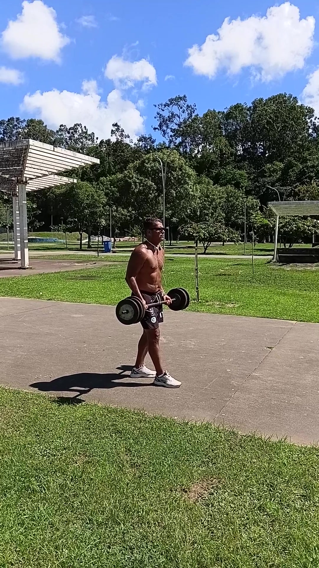 Eduardo Paiva realizando exercício de força com barra ao ar livre
